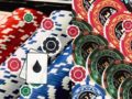 Pile of casino poker chips in red, blue, and white with a playing card showing a black water droplet icon in the foreground.